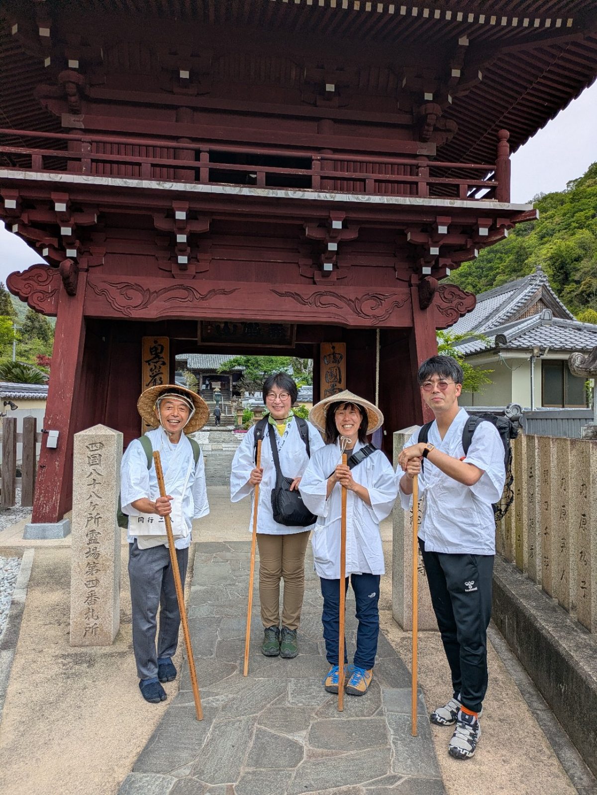 札所の山門の前で金剛杖を持つお遍路さんたち