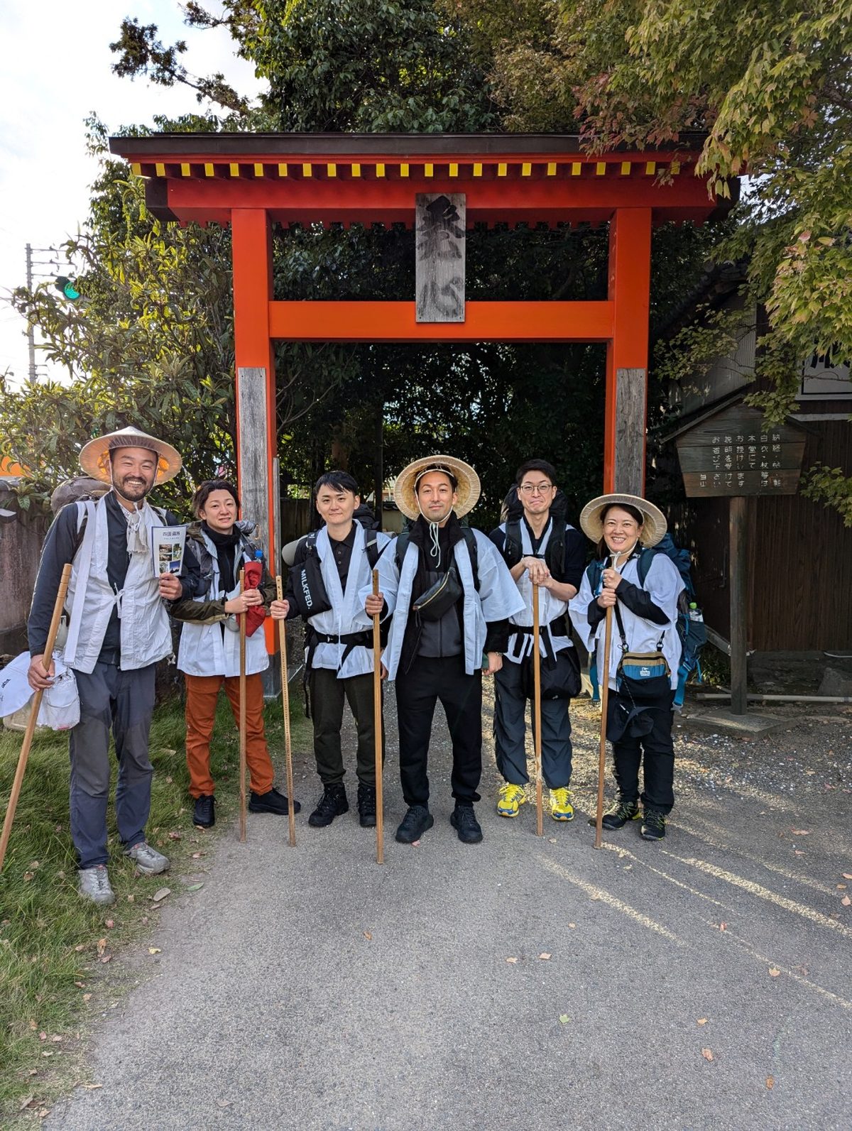 朱色の山門の前で笑顔のお遍路一行